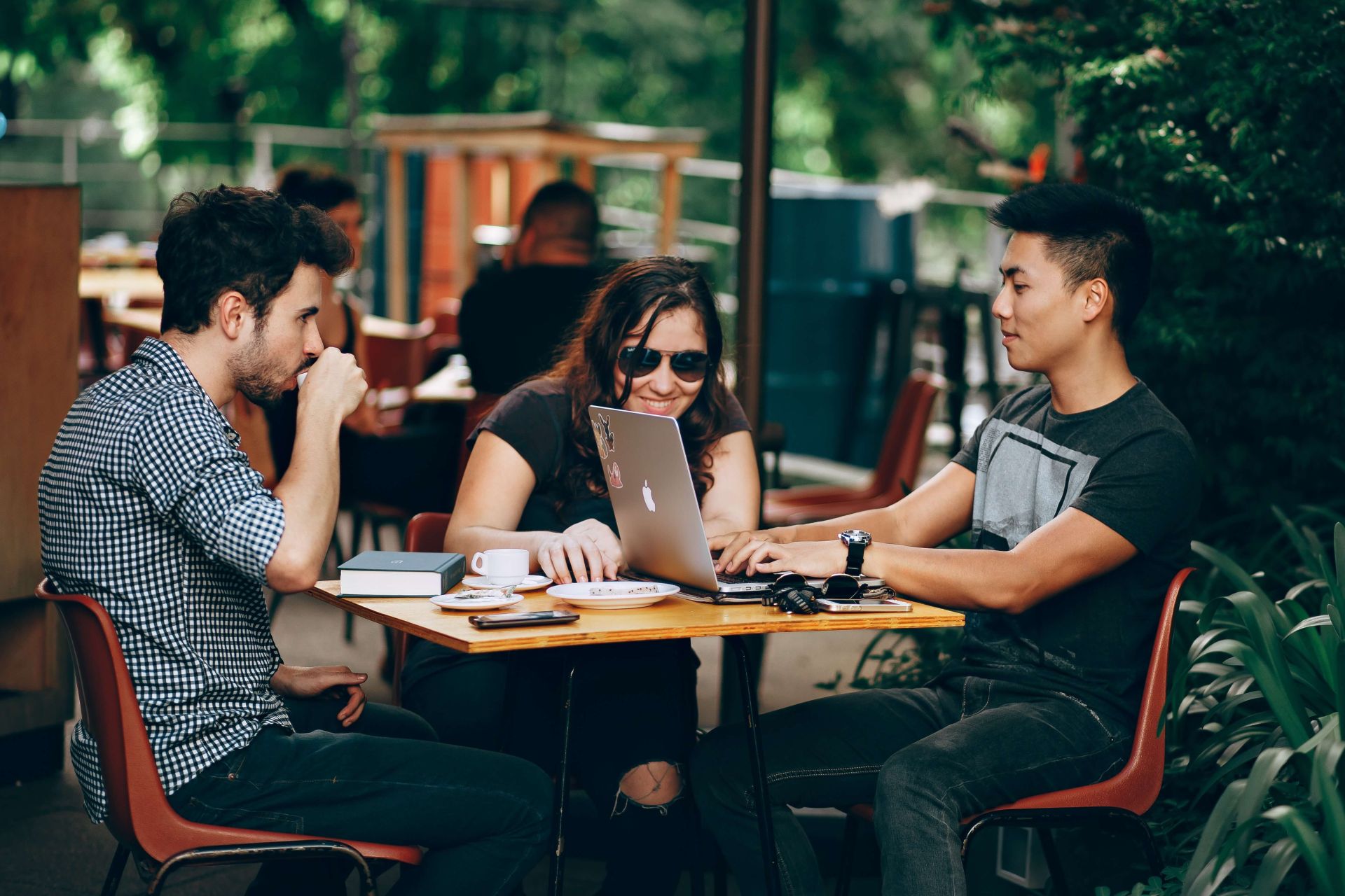 Banner com três jovens sentados numa mesa de café a interagir